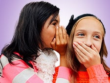 One girl whispering to another girl to her ear. 